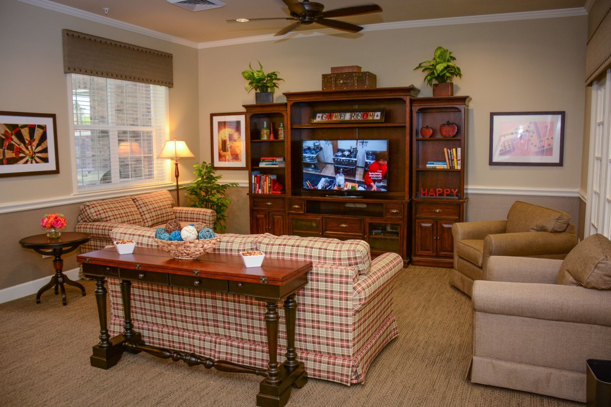 Cozy living room with a television, plaid sofas, and wooden furniture.