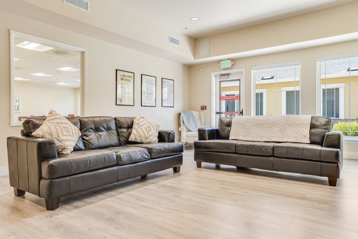 A modern living room with two brown sofas and wooden flooring.