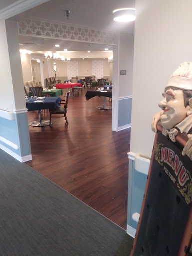 A spacious dining area set up for an event, featuring tables and a decorative statue.