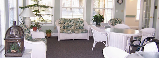 A cozy living space featuring a floral-patterned sofa, accompanied by a plant and a dining table.