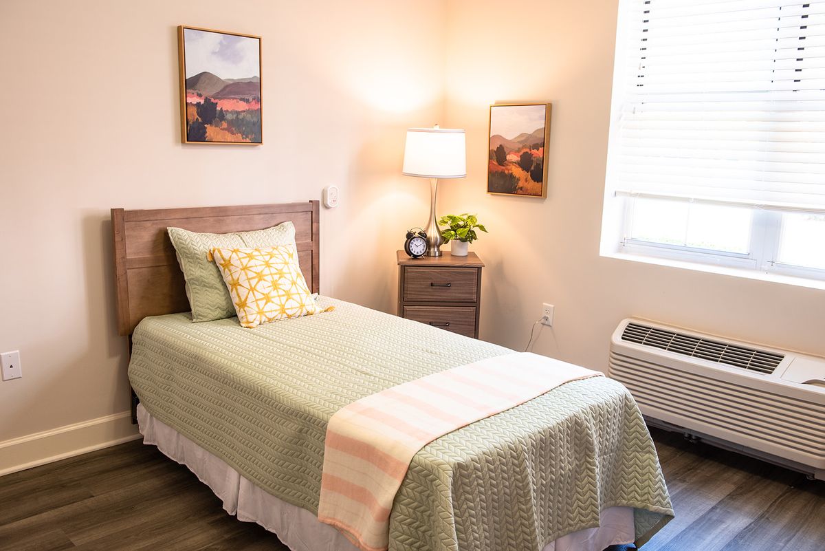 A cozy and minimalist bedroom with a single bed, lamp, and simple decor.