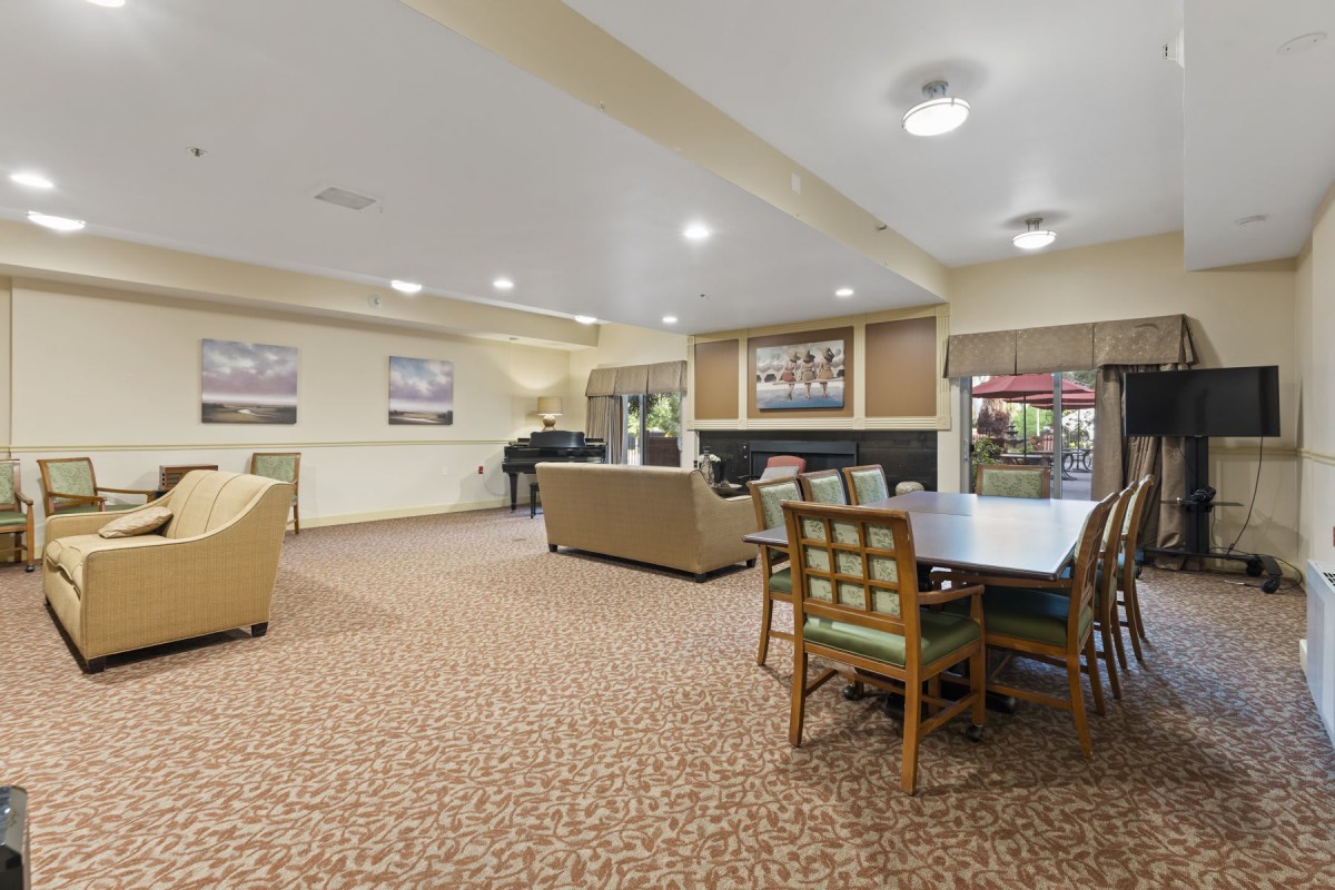 A spacious lounge area with comfortable seating, a piano, and a dining table.