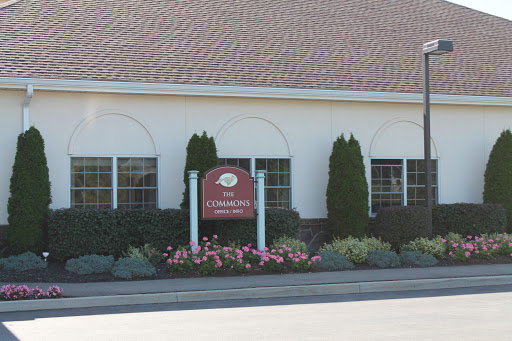 The exterior of a building featuring a welcoming sign and landscaped flower beds.