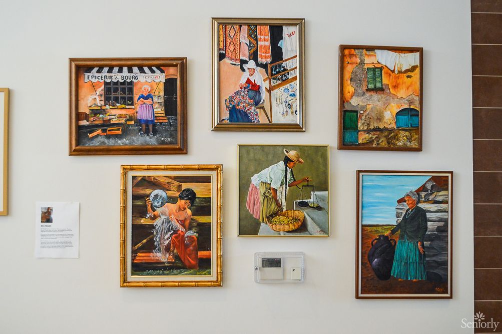 A collection of colorful paintings displayed on a wall, each depicting various scenes and figures in vibrant frames.