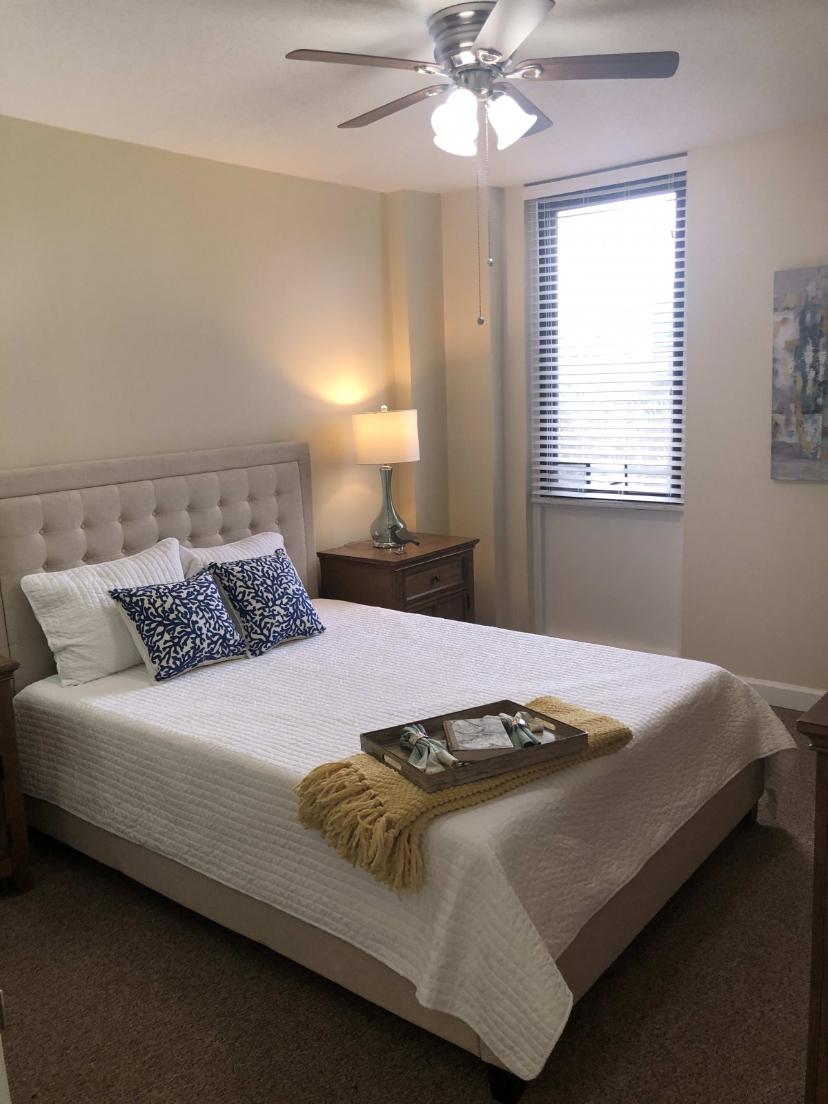 A cozy bedroom with a neatly made bed, stylish pillows, and soft lighting.