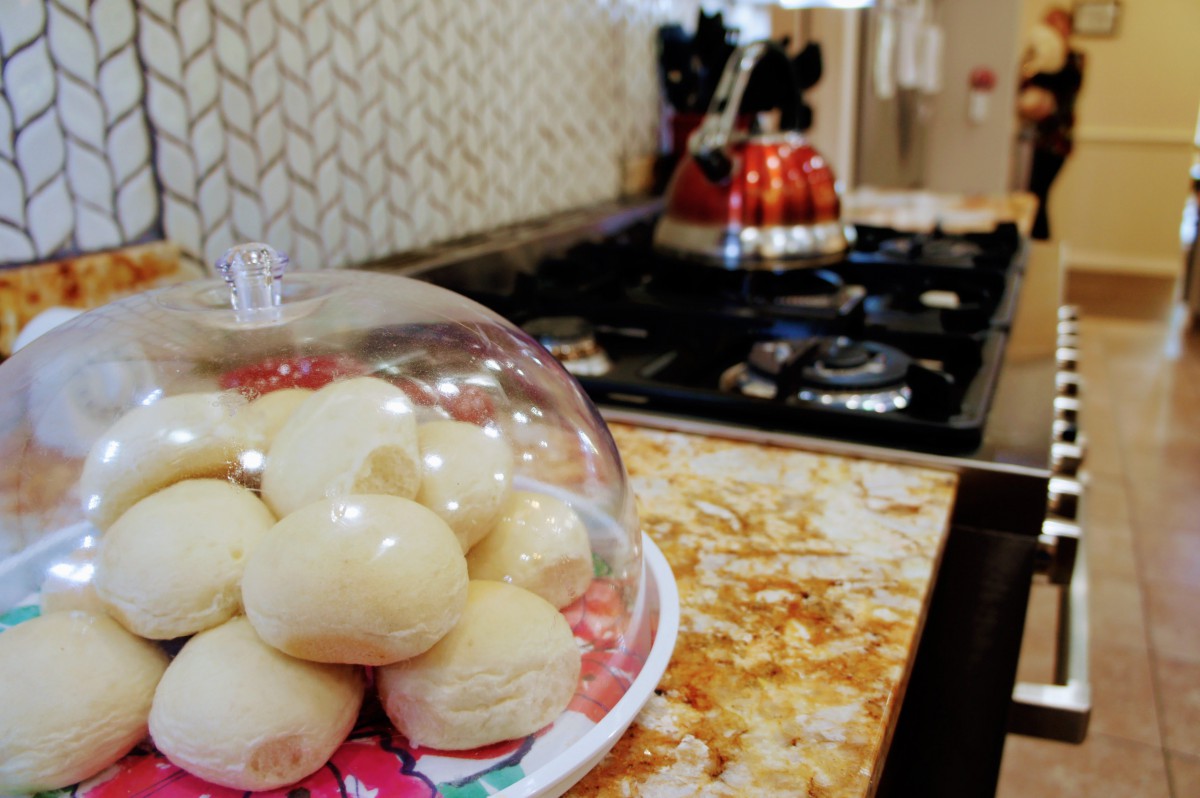 A kitchen with freshly baked bread rolls under a glass dome on the countertop.