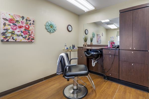 A cozy beauty salon interior featuring a styling chair, mirror, and wall decorations.