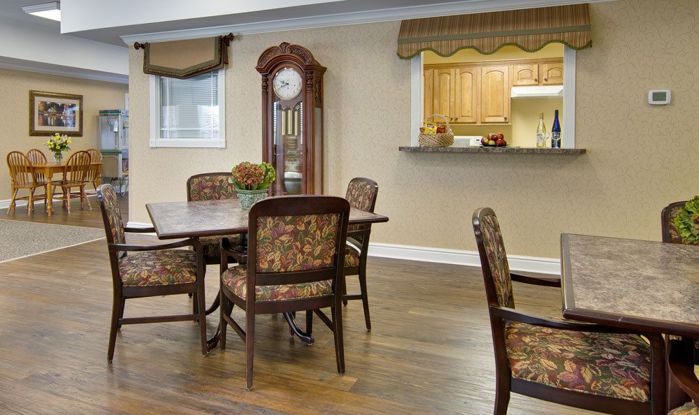 A cozy dining area with a wooden table and chairs, featuring a grandfather clock and a kitchen pass-through.