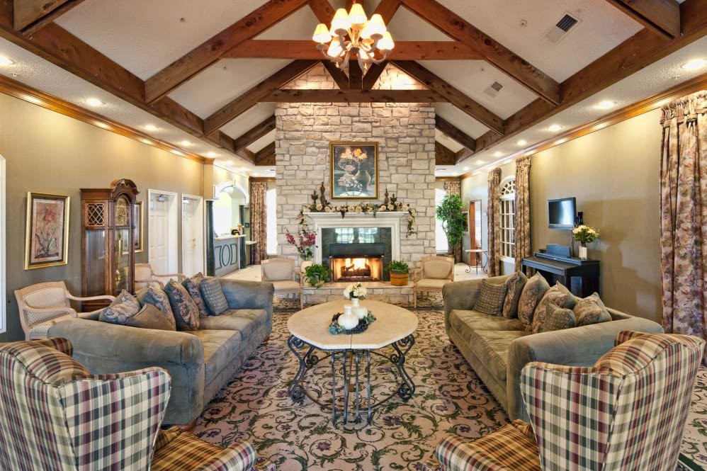 A warm and inviting living room with a traditional design, featuring a vaulted ceiling, stone fireplace, and elegant chandelier.