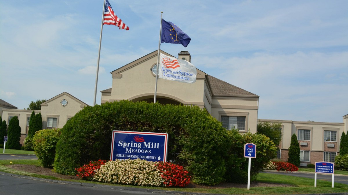 Entrance of the Spring Mill Manor with flags and a handicap parking spot.