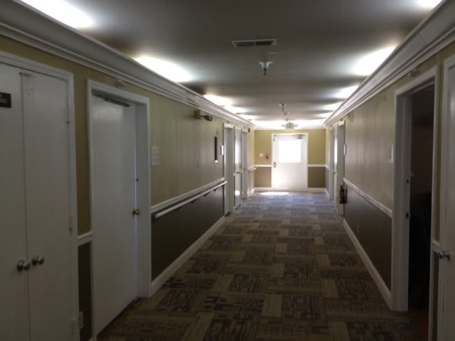 A well-lit hallway with several doors and patterned carpeting.
