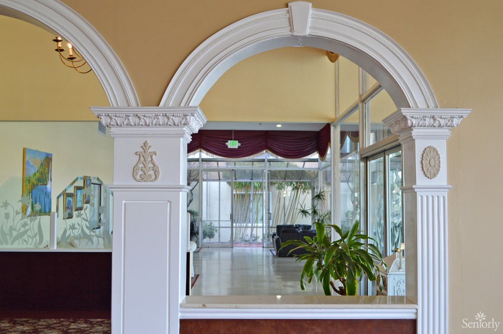 A hotel lobby featuring an ornate archway and indoor plants.