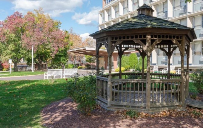 A scenic garden with a wooden gazebo and benches under a clear blue sky.