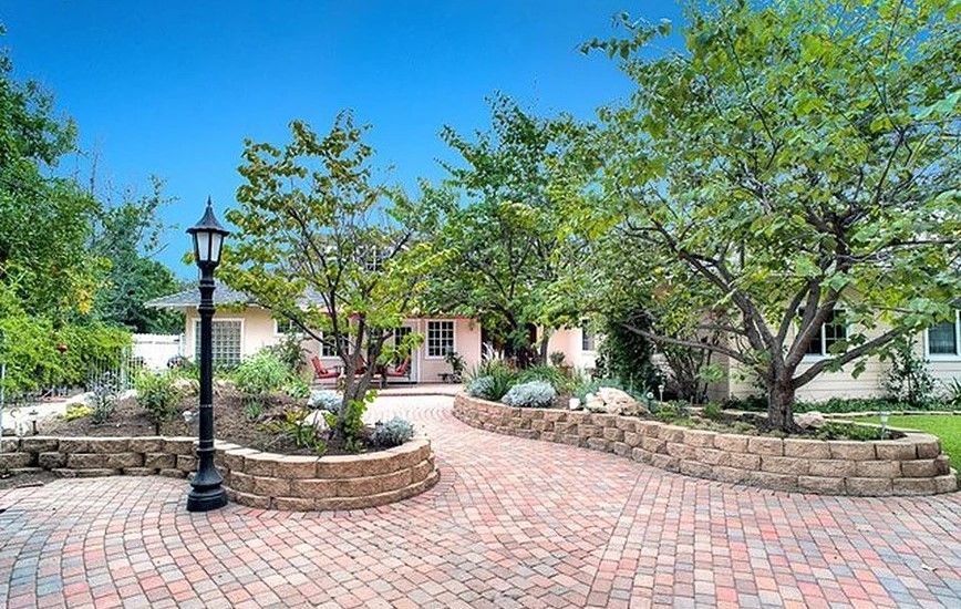 A charming house with a brick driveway and lush garden.