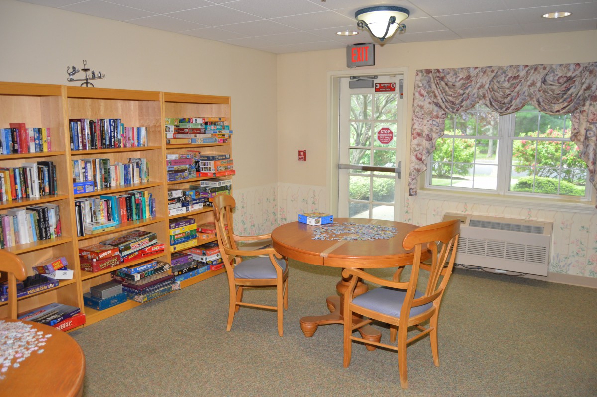 A cozy library space with bookshelves, a round table, and chairs.