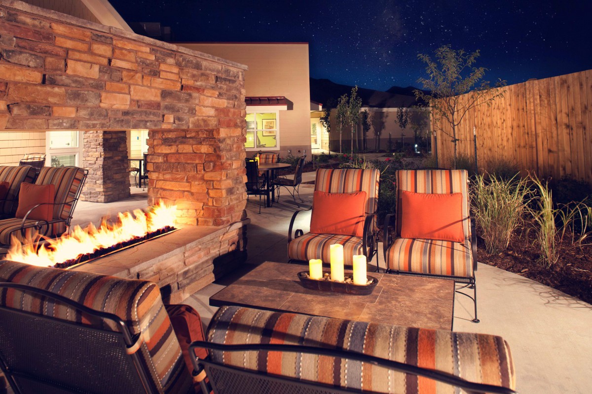 A cozy outdoor patio area with a lit fireplace and comfortable seating at night.