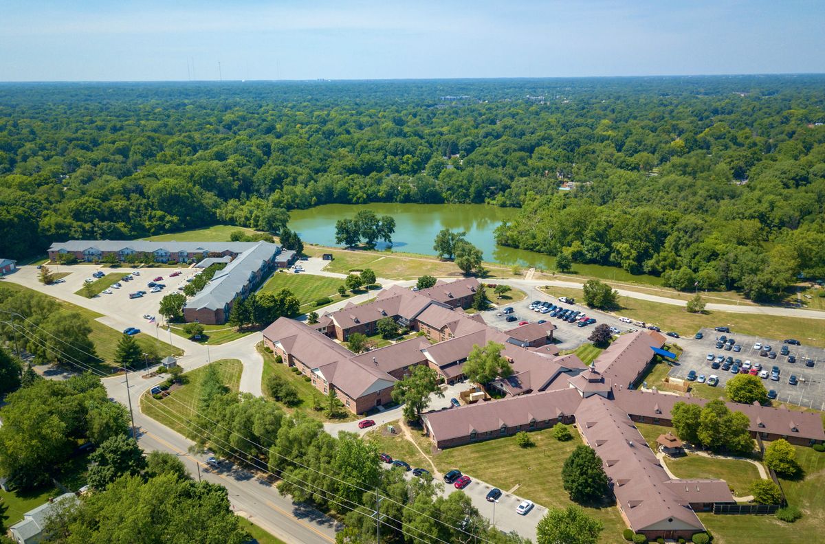 Aerial view of a complex surrounded by lush greenery and a nearby lake.