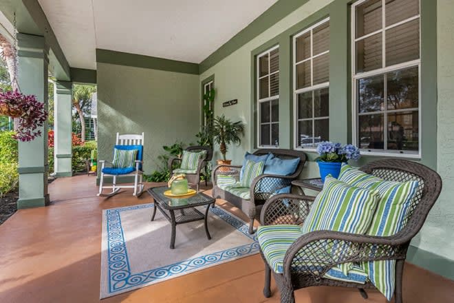 A cozy porch with green walls, comfortable seating, and decorative plants.