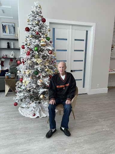 A person seated near a beautifully decorated Christmas tree.