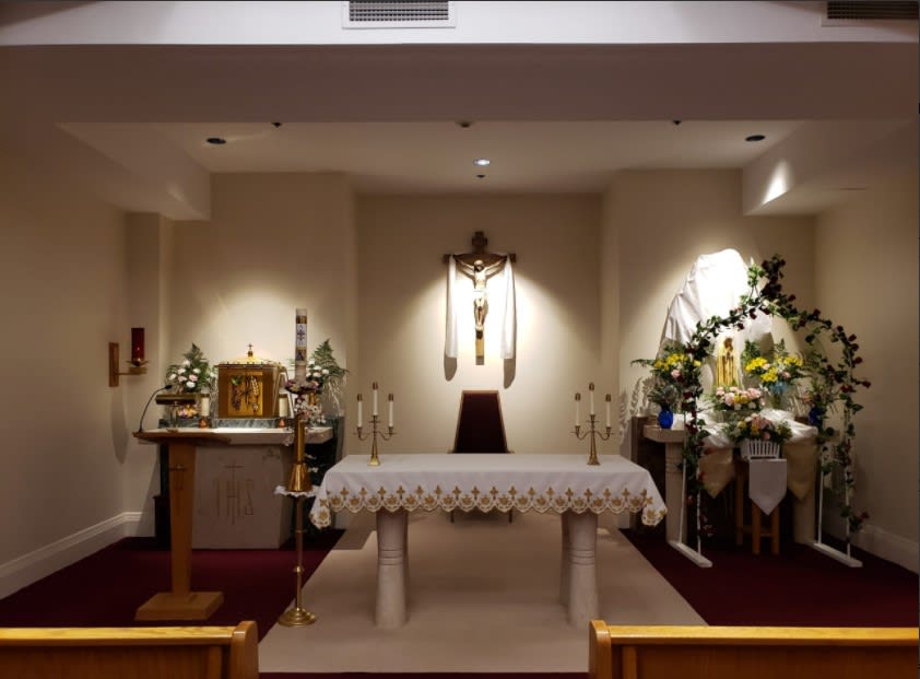 A church altar with a crucifix, adorned with flowers and candles.