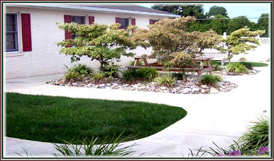 A beautifully maintained garden with a lush green lawn, various trees and shrubs, and a clean pathway leading around the area.