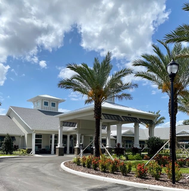 A scenic view of a modern building surrounded by palm trees under a partly cloudy sky.