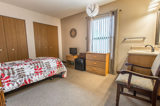 A cozy and well-furnished bedroom featuring a bed, dresser, and study desk.