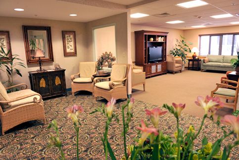 A cozy lobby with seating, a TV, and decorative plants.