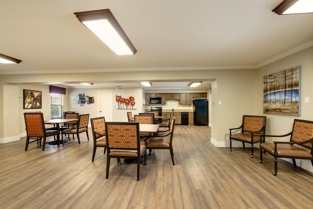 A modern dining area with wooden flooring and seating arrangement, adjacent to a kitchen space.