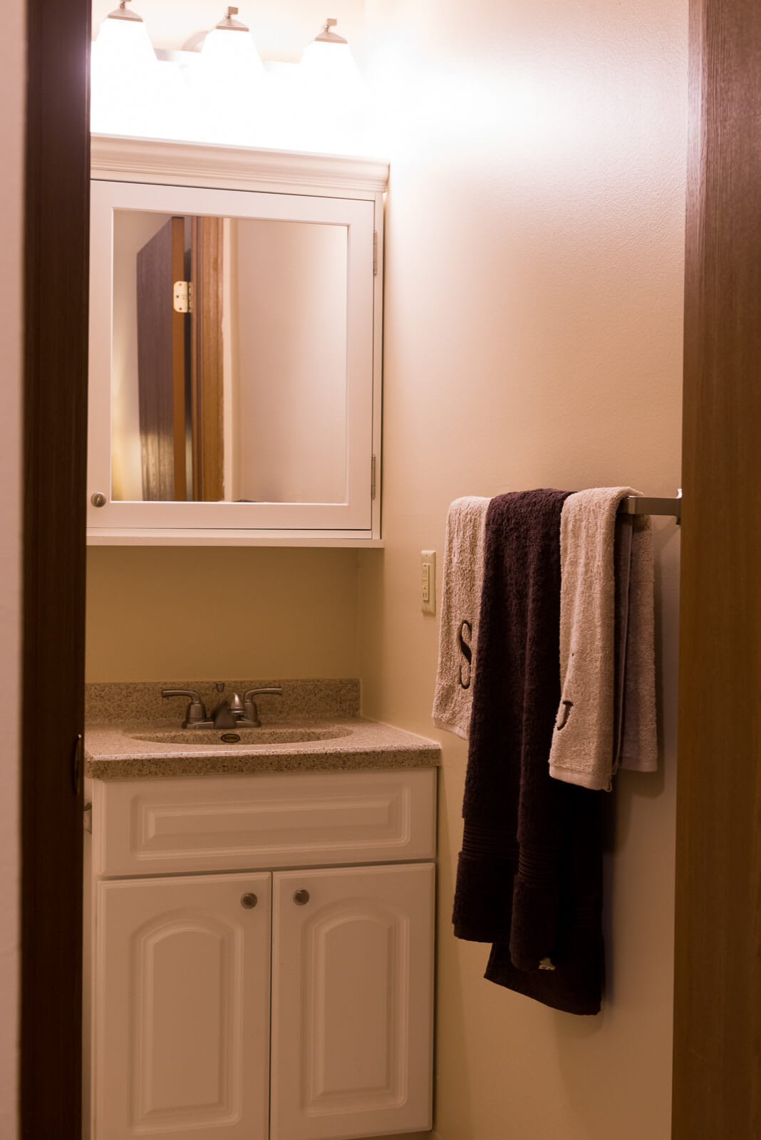 A bathroom with a vanity sink, mirror, and neatly hung towels.