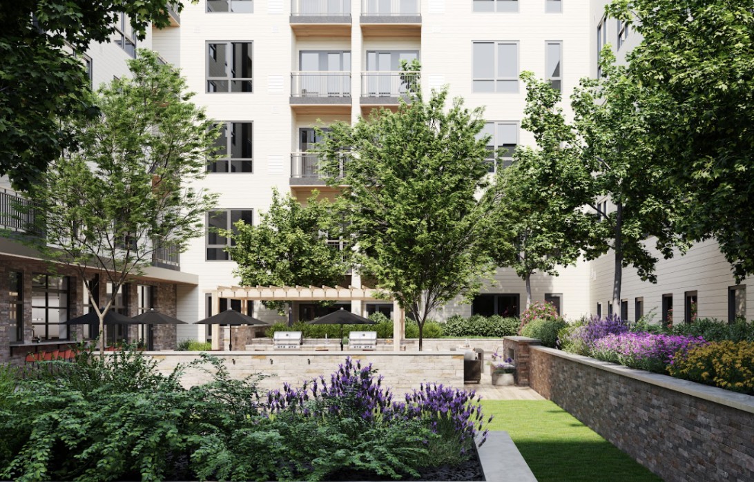A modern apartment building with a well-maintained courtyard featuring lush greenery and outdoor seating.
