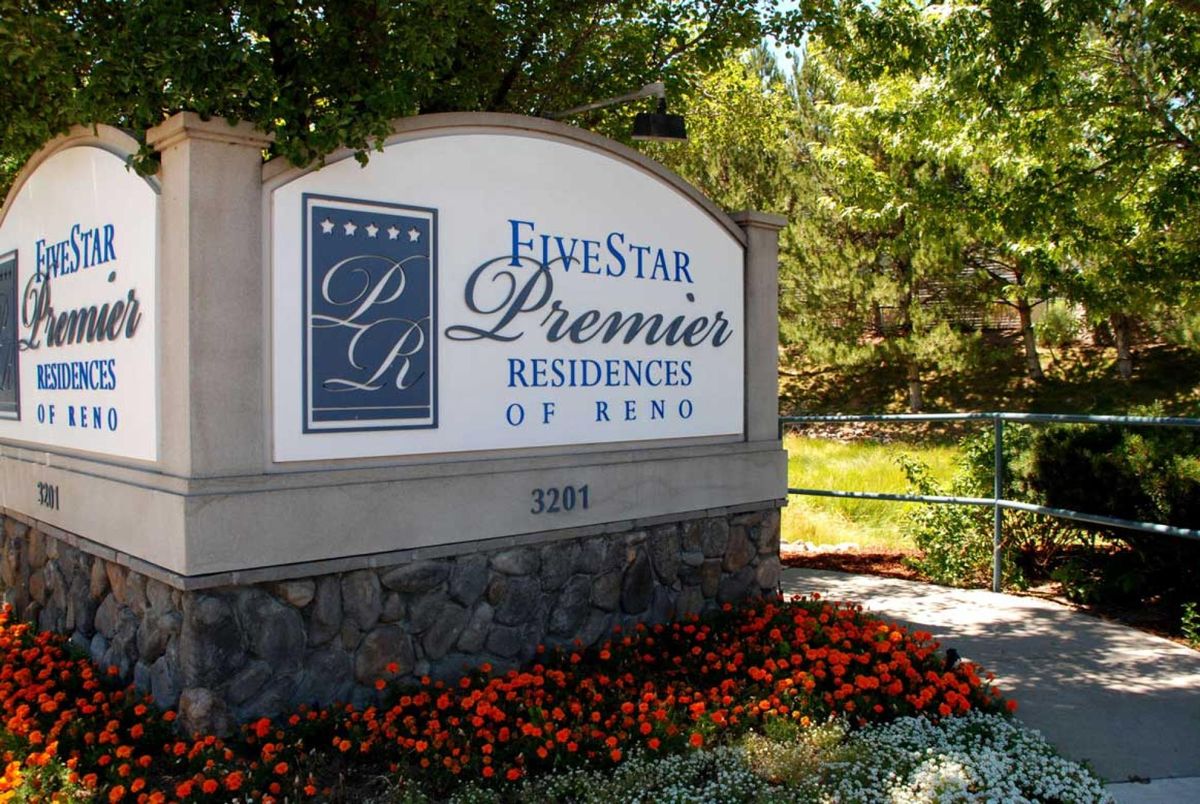 Entrance sign for Five Star Premier Residences of Reno surrounded by trees and flowers.