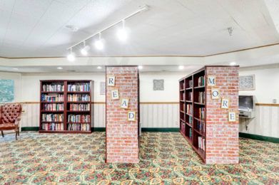 A cozy library with brick pillars and numerous bookshelves filled with books.