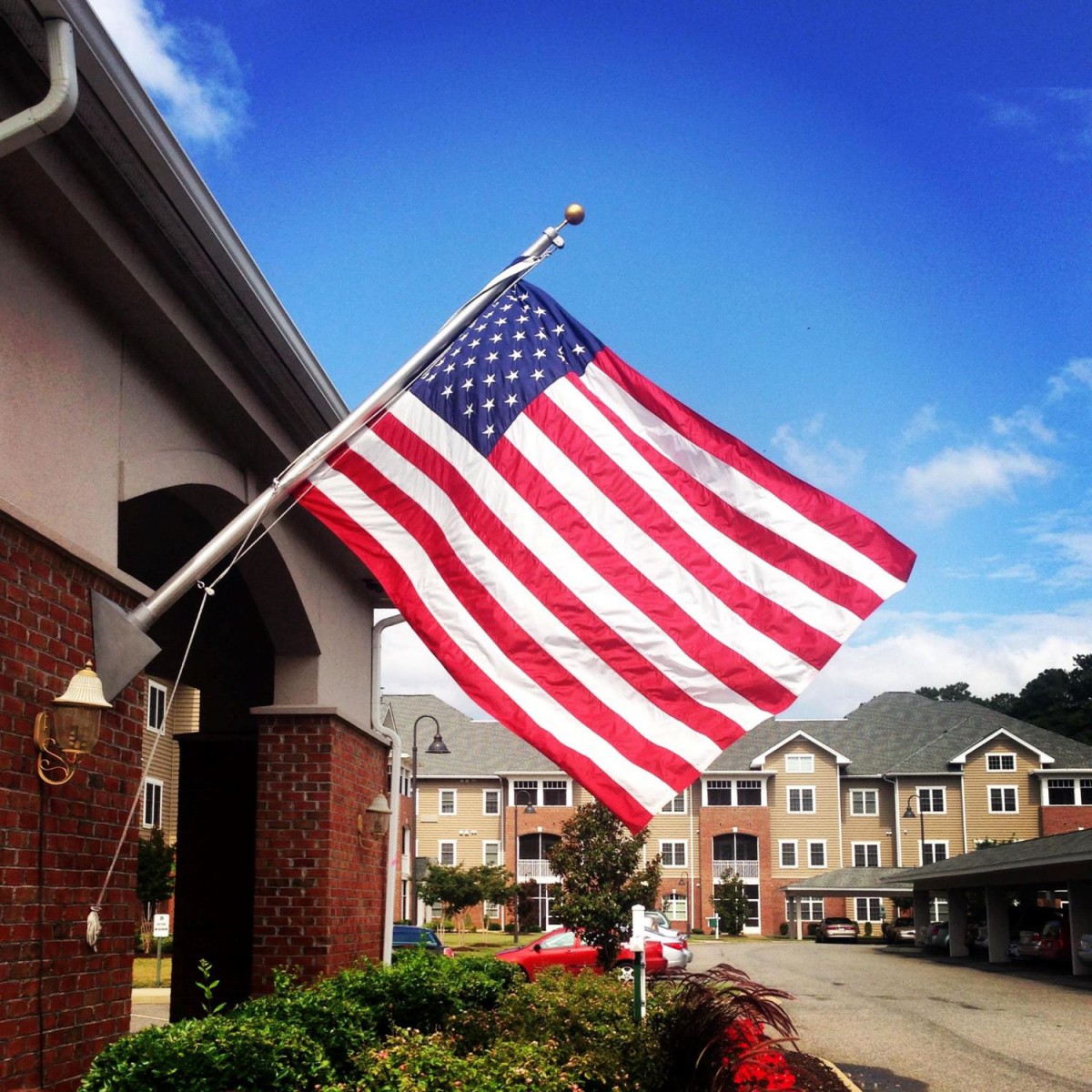 An American flag waving outside a building under a clear blue sky.