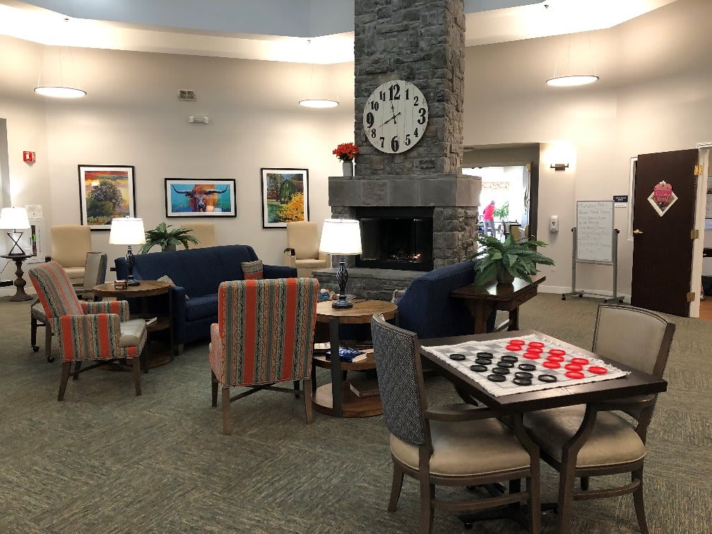 A cozy lounge area featuring a fireplace, game table, and comfortable seating.