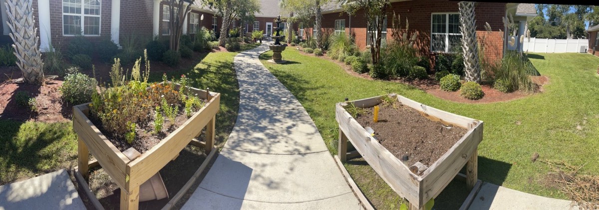 A serene garden path lined with planters and greenery, featuring a central fountain.