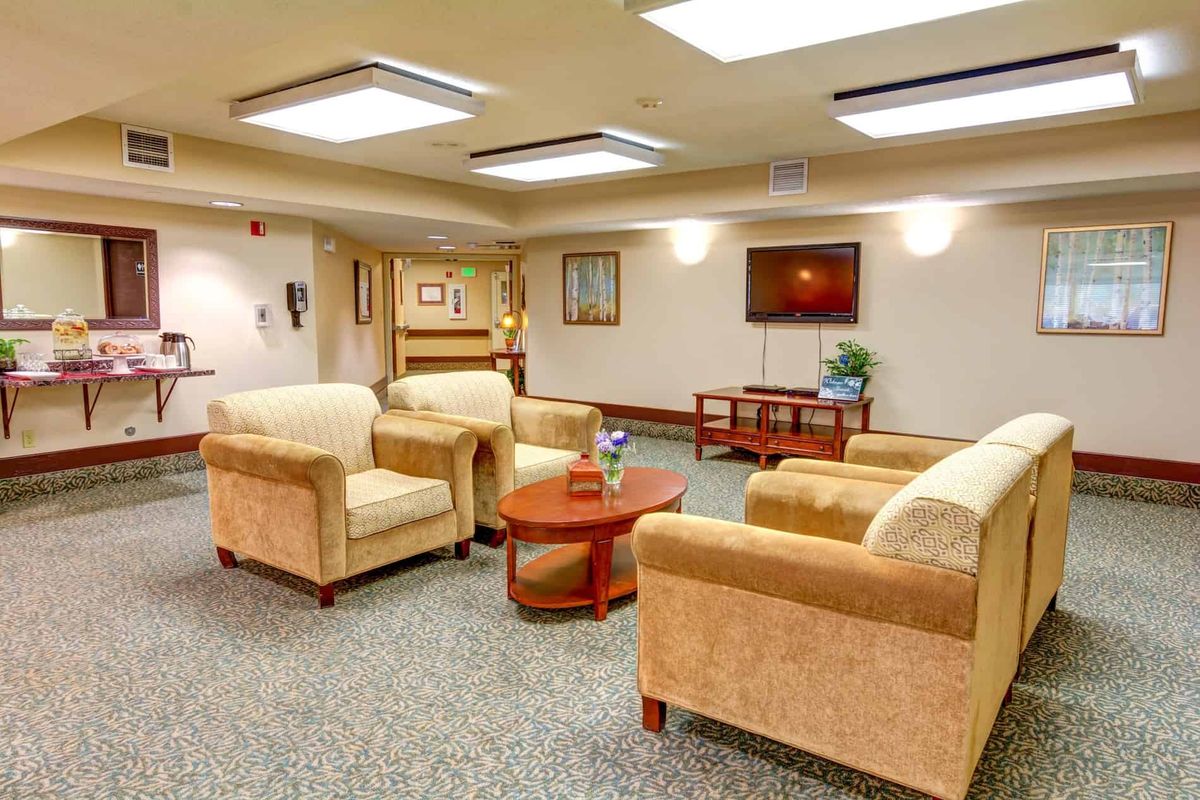 A comfortable lobby with plush chairs, sofas, and a coffee table, featuring a television and artwork on the walls.