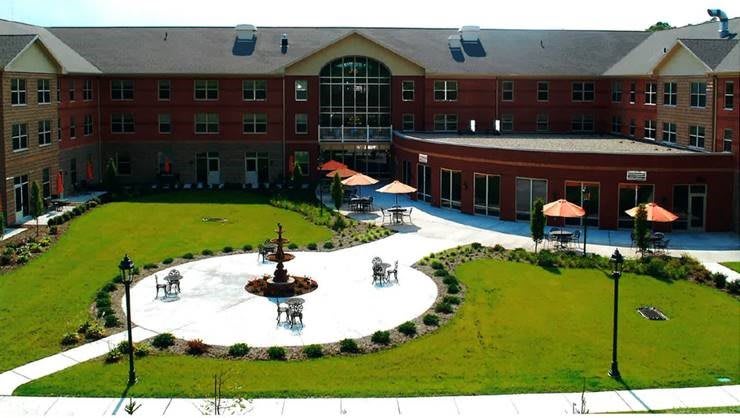 A courtyard with a central fountain, surrounded by a well-maintained lawn and seating areas.