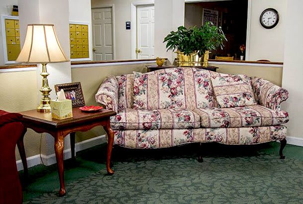 A cozy living room with a floral upholstered couch, side table, and lamp.