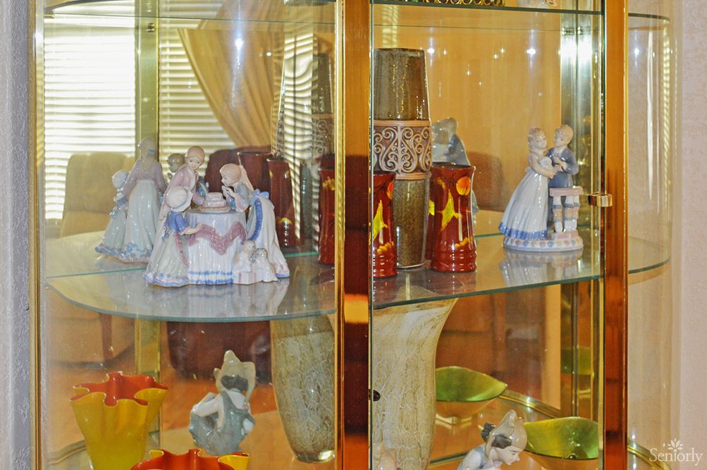 A showcase of porcelain figurines and antiques in a glass display case.