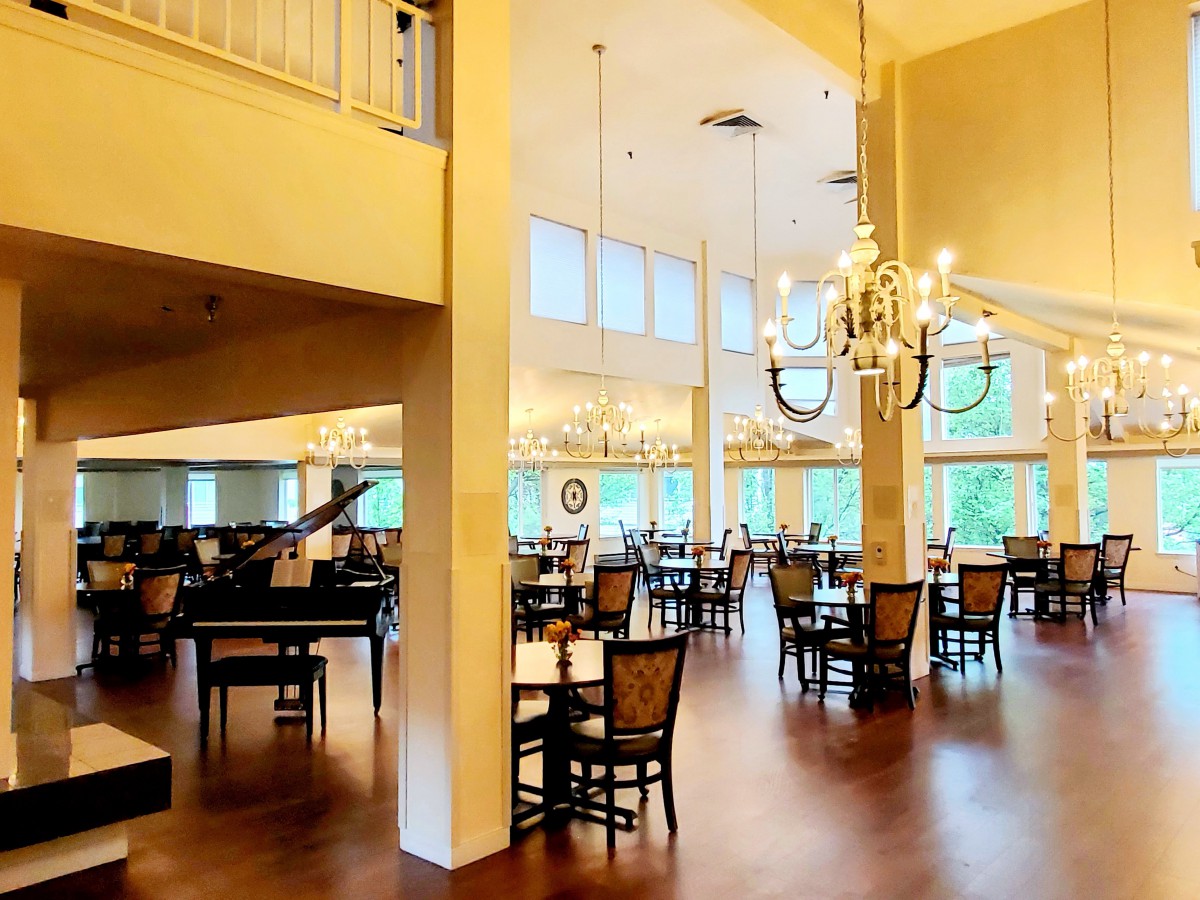 A spacious dining area with elegant chandeliers and neatly arranged tables and chairs.