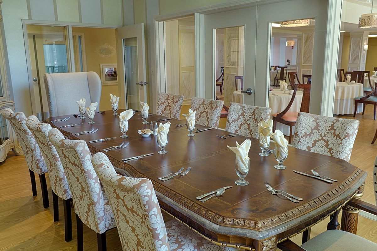 An elegantly set dining room with a large wooden table and ornate chairs, ready for formal dining.