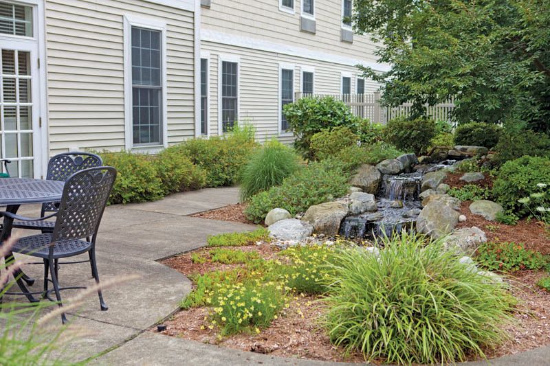 A beautifully landscaped garden with a water feature and patio seating.