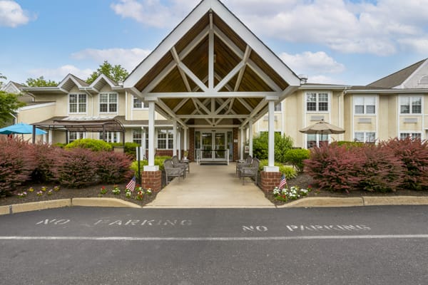 A welcoming building entrance with a covered porch and landscaped surroundings.
