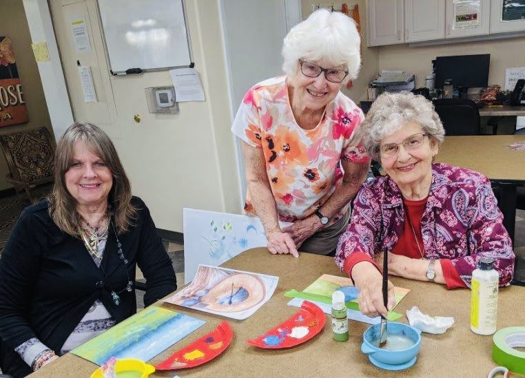 A group of seniors enjoying a painting activity together indoors.