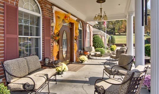 A cozy porch adorned with fall decorations and comfortable seating.
