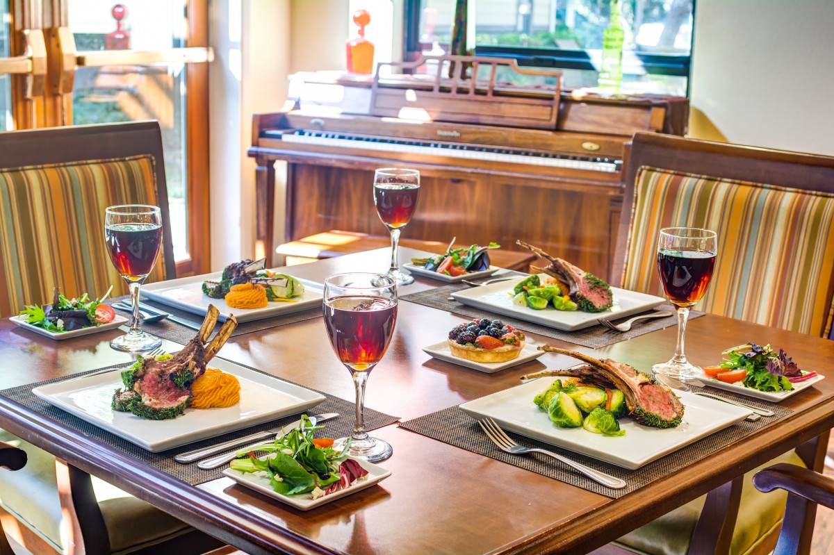 A beautifully set dining table with gourmet meals and glasses of red wine, ready for an elegant meal.