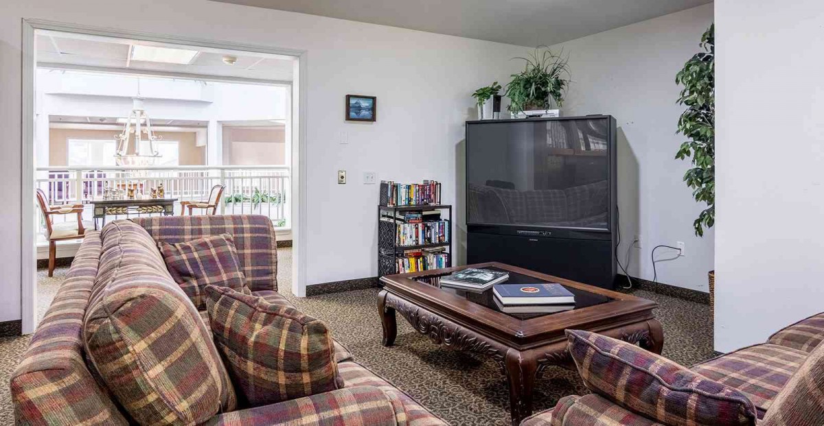 Cozy living room with a large TV, plaid sofas, and a wooden coffee table.