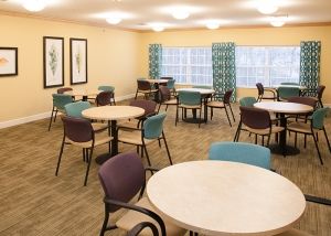 An empty dining room with round tables and colorful chairs.