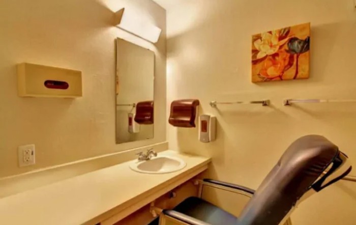 A small bathroom with a sink, mirror, and towel dispenser.